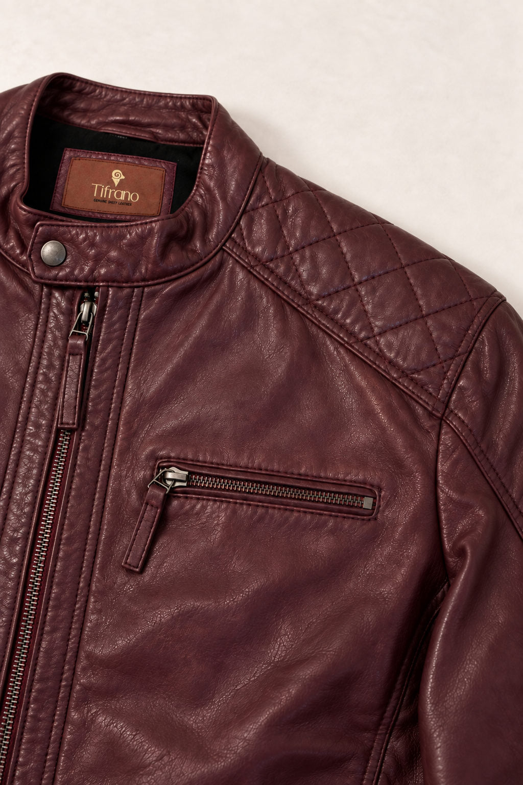 Close-up of the Tifrano Prague burgundy leather jacket showing the quilted shoulder, snap collar, chest zip and leather texture.
