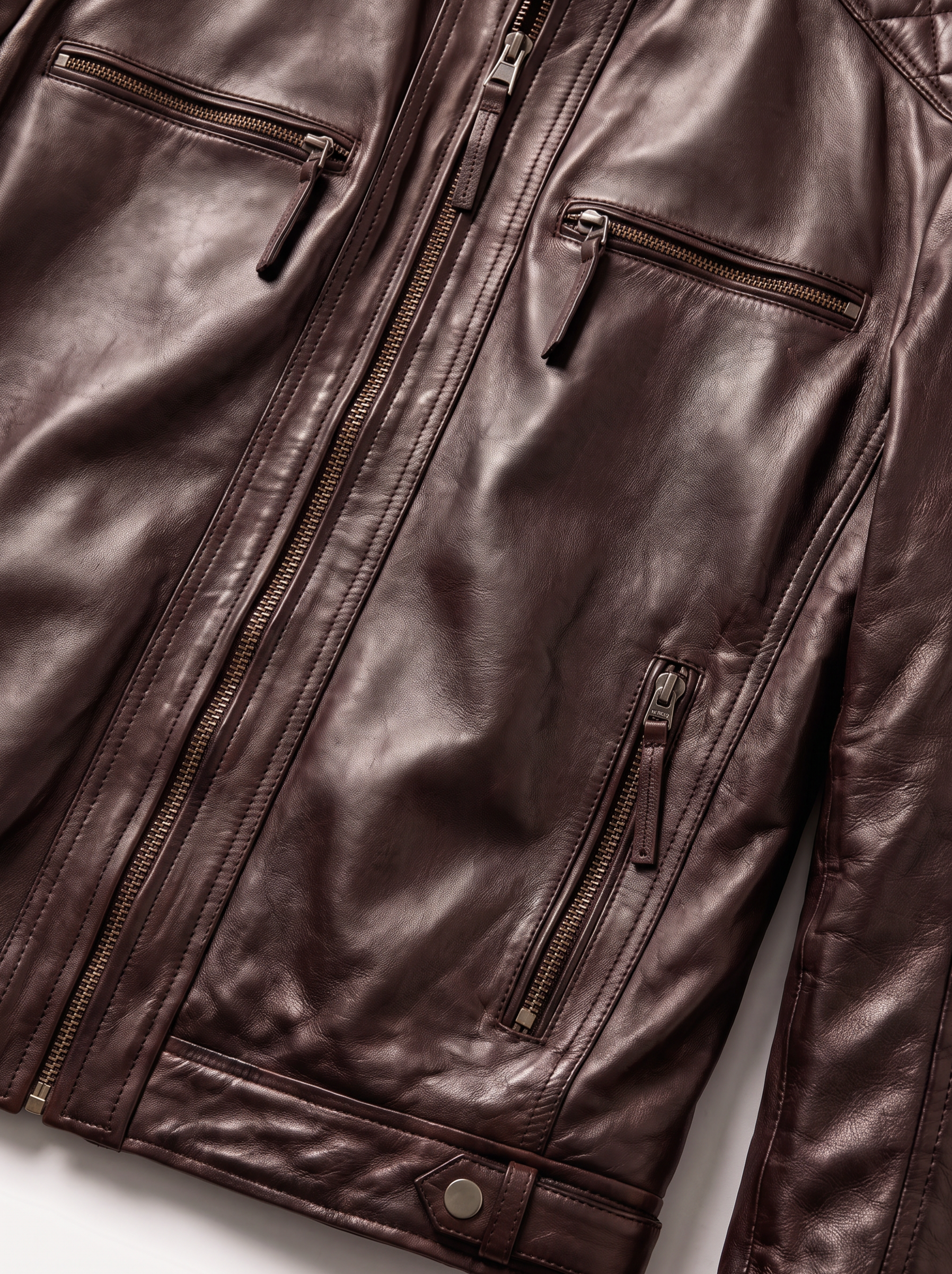 Close-up of a dark brown leather jacket with multiple zippered pockets and a front zipper, shown against a plain light background.