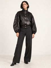 Woman wearing the Electra black leather jacket with puff sleeves, full-body front view